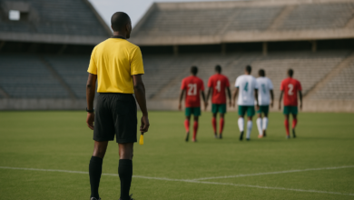 Campo de futebol vazio com árbitro e jogadores desfocados após partida internacional