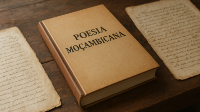 Livro de poesia moçambicana sobre mesa de madeira junto a manuscritos antigos