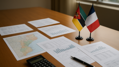 Documentos financeiros sobre mesa de reunião com mapa de Moçambique e bandeiras francesa e moçambicana
