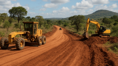 Estrada em construção junto a equipamentos de obras públicas numa paisagem moçambicana
