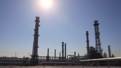 Instalações industriais de extracção de petróleo com torres e tubagens sob céu limpo ao pôr do sol