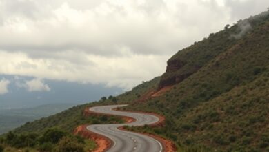 Estrada de terra sinuosa atravessando uma paisagem montanhosa sob um céu nublado ao entardecer sem pessoas.