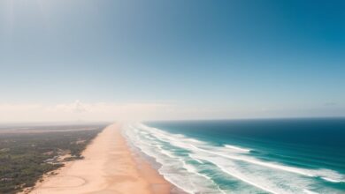 Vista aérea da paradisíaca Praia do Tofo em Moçambique com ondas suaves e areia dourada sob sol brilhante
