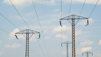 Linhas de alta tensão e postes de distribuição eléctrica sob céu aberto em paisagem moçambicana rural
