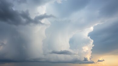 Céu com nuvens densas de tempestade sobre uma vasta paisagem agrícola durante o entardecer.