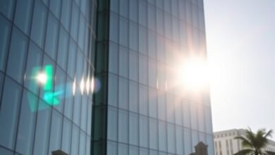 Edifício moderno de instituição financeira internacional refletido num vidro límpido sob luz natural matinal.