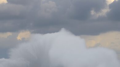 Ondas gigantes e ventos fortes atingem a orla costeira sob um céu carregado de nuvens tempestuosas.
