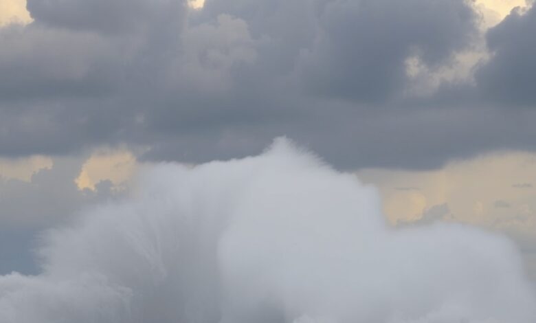 Ondas gigantes e ventos fortes atingem a orla costeira sob um céu carregado de nuvens tempestuosas.
