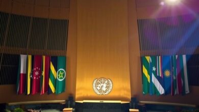 Púlpito de madeira polida diante do plenário iluminado da Assembleia Geral da ONU com bandeiras internacionais ao fundo.
