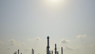 Instalações industriais de refino de petróleo e tanques de armazenamento sob céu nublado ao pôr do sol