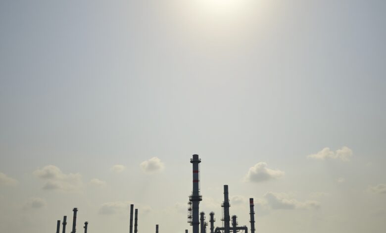 Instalações industriais de refino de petróleo e tanques de armazenamento sob céu nublado ao pôr do sol