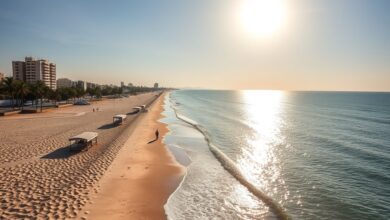 Vista panorâmica da praia da Costa do Sol em Maputo com faixa de areia e mar calmo sob sol radiante.