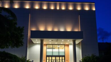 Fachada exterior iluminada de um edifício moderno de tribunal de justiça com bandeiras hasteadas ao anoitecer.